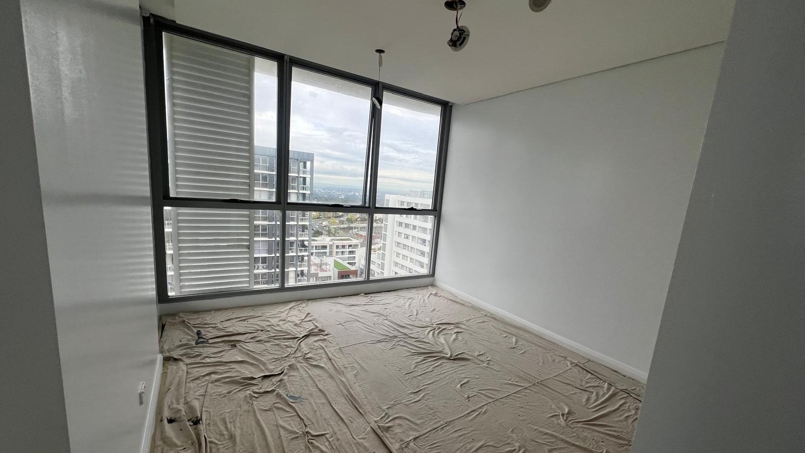 Apartment room with the walls and ceiling set flush and the floor sheeted over before painting