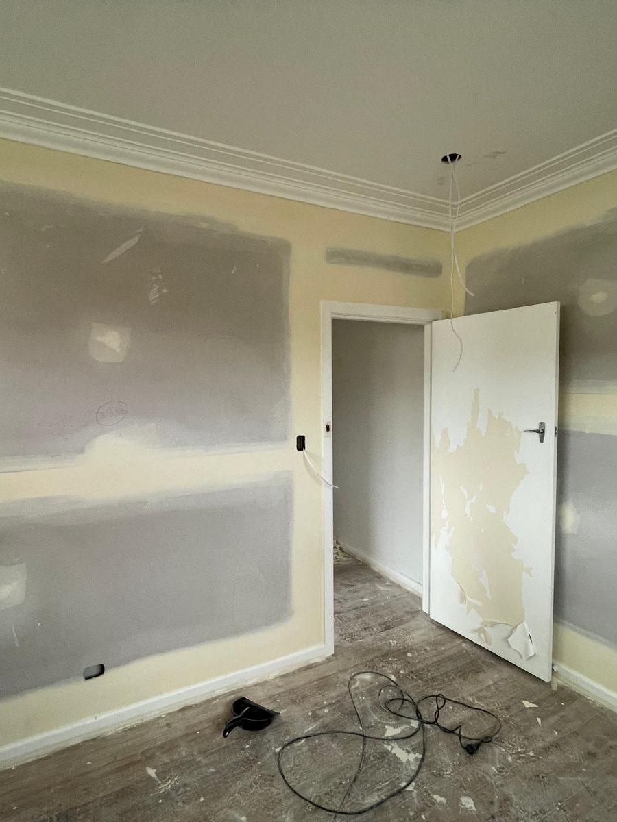 Bedroom with every plasterboard joint taped and topped and the cornice run, the floor still bare and the room ready for paint
