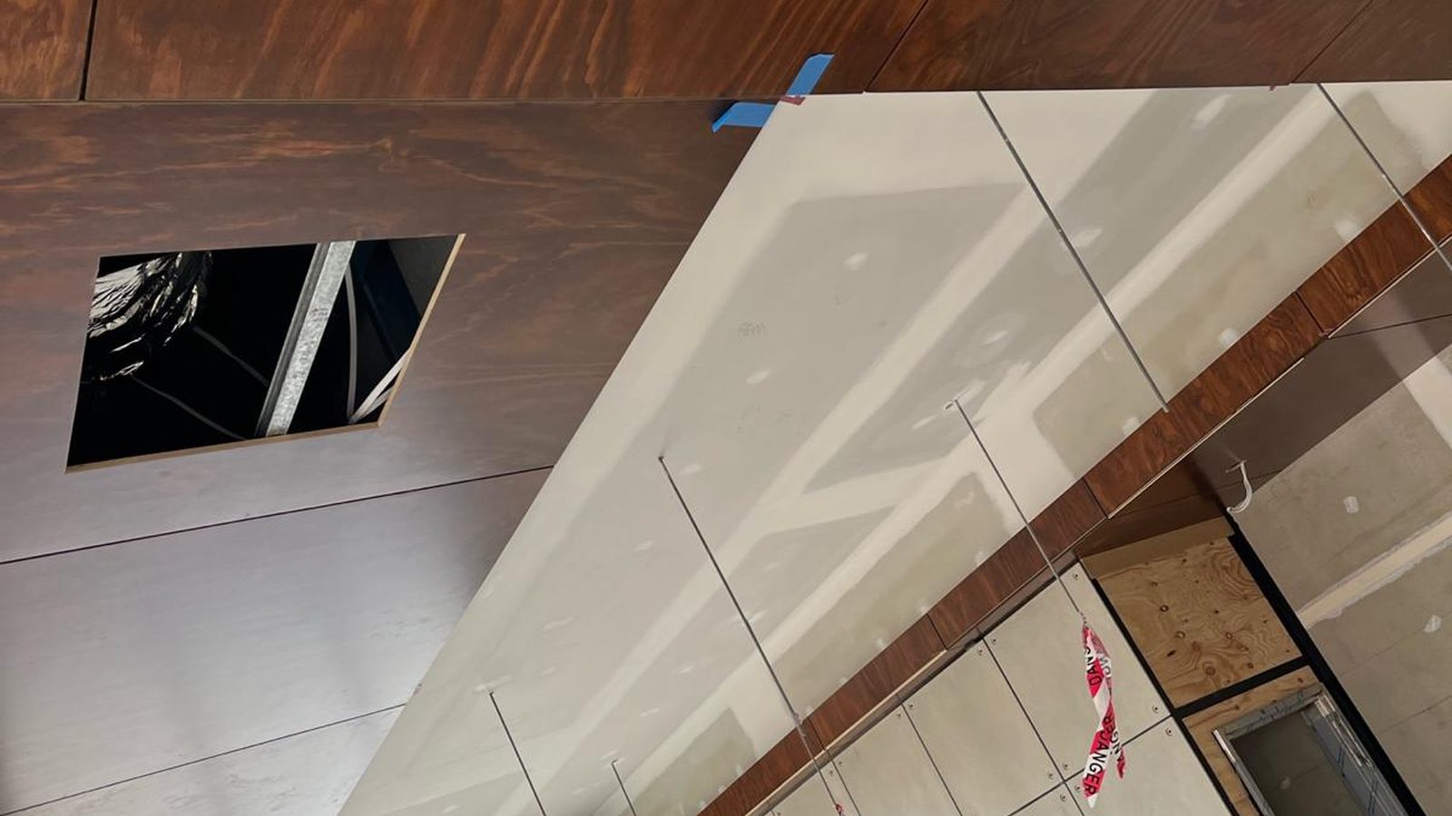 Bulkhead with crisp square edges set against a timber lined ceiling, with a service opening left open