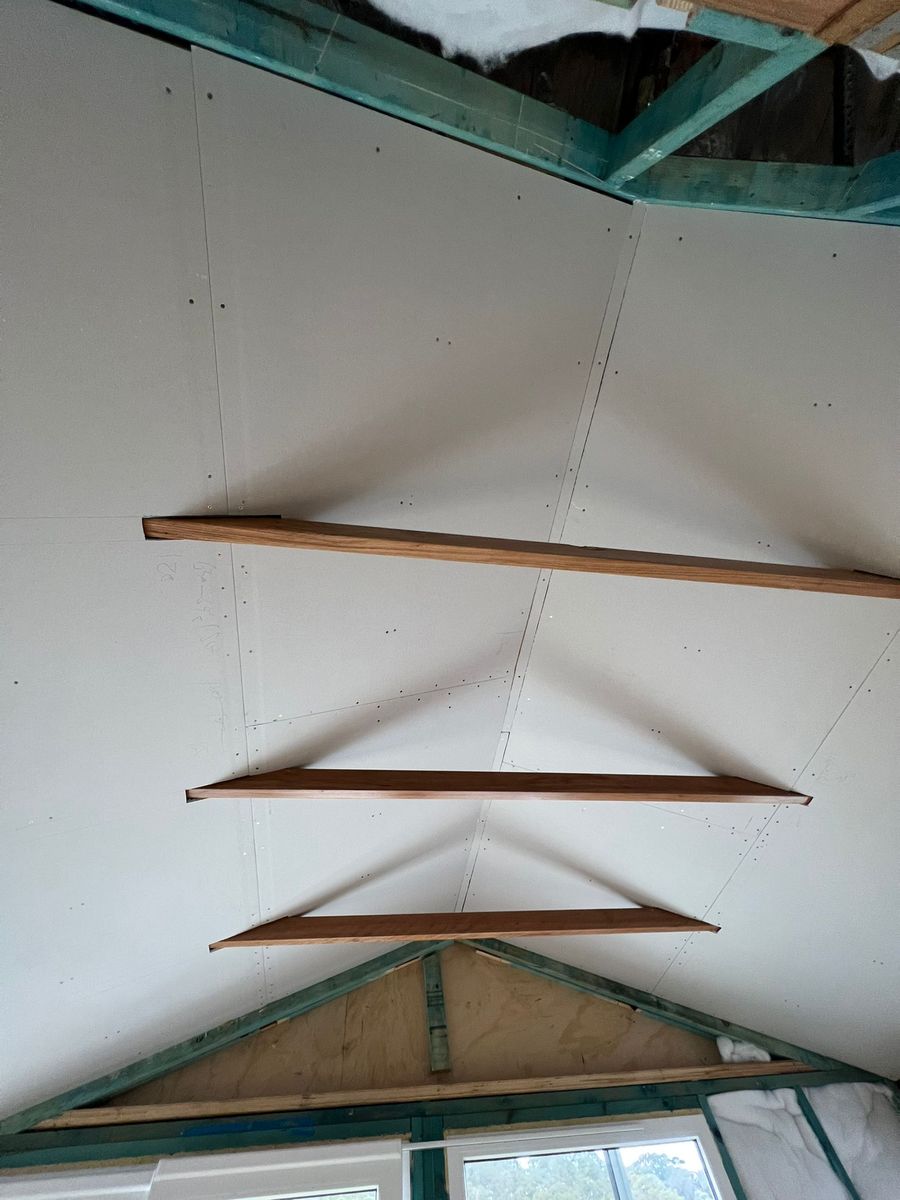Raked cathedral ceiling newly sheeted in plasterboard with screw fixings and pencil setting-out marks visible, and exposed stained timber beams running across the room