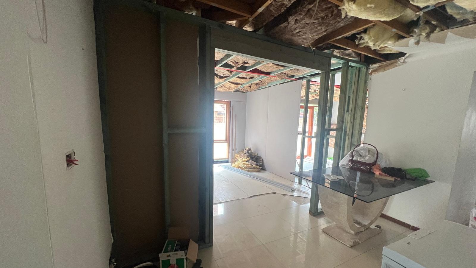 Room with the ceiling opened around a new steel beam and the wall linings cut back