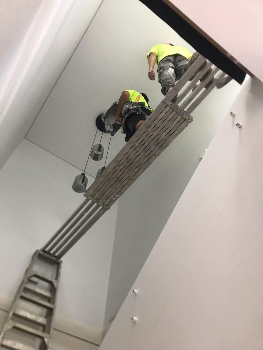 Ceiling opening with a fold down ladder, with two workers in the roof space above