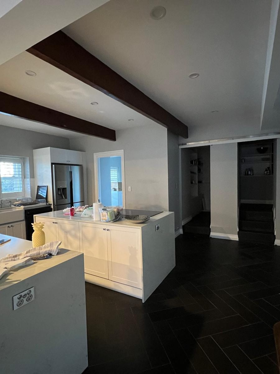 Kitchen and living area where the ceiling has been set flush on both sides of exposed timber beams