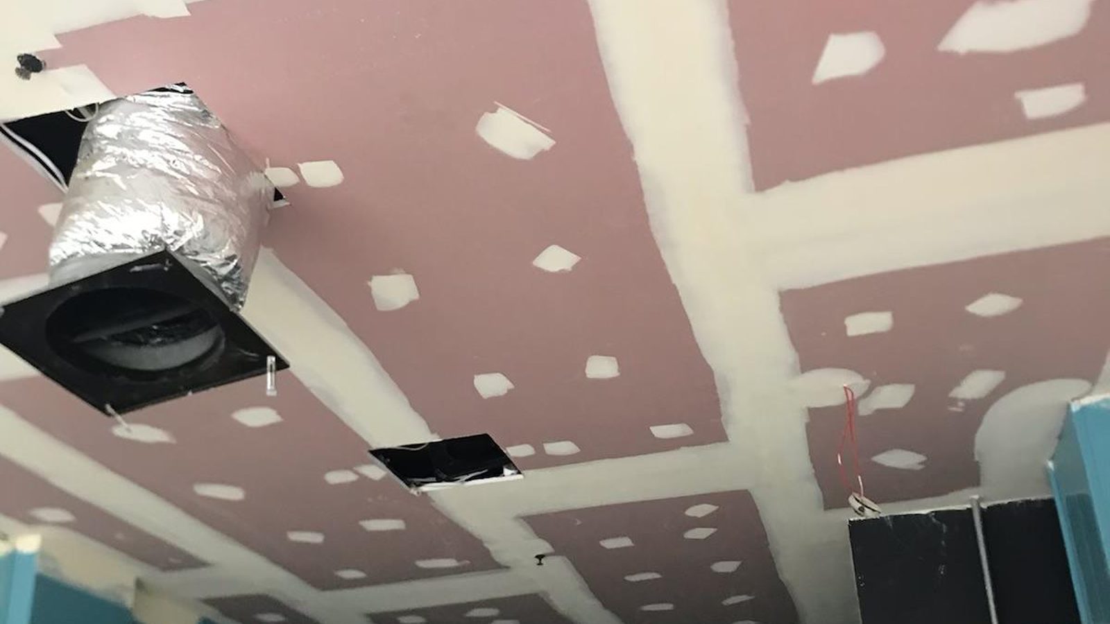 Ceiling sheeted and the screw fixings spotted around flexible ducting and an air outlet before the joints are finished