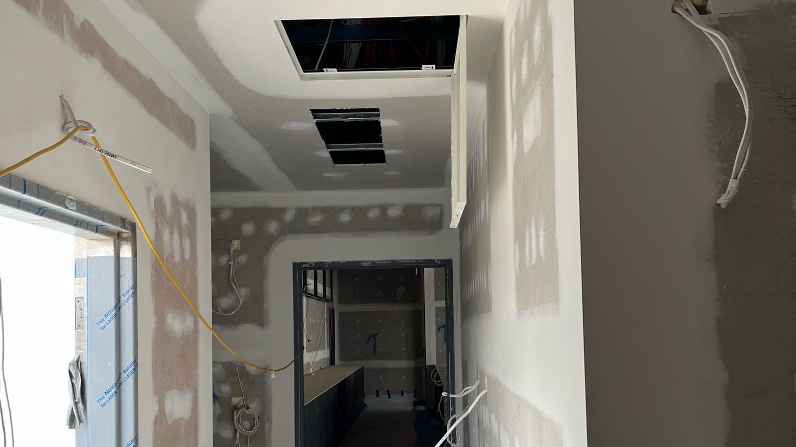 Ceiling and walls sheeted and coated around air outlets and cabling in a fit out