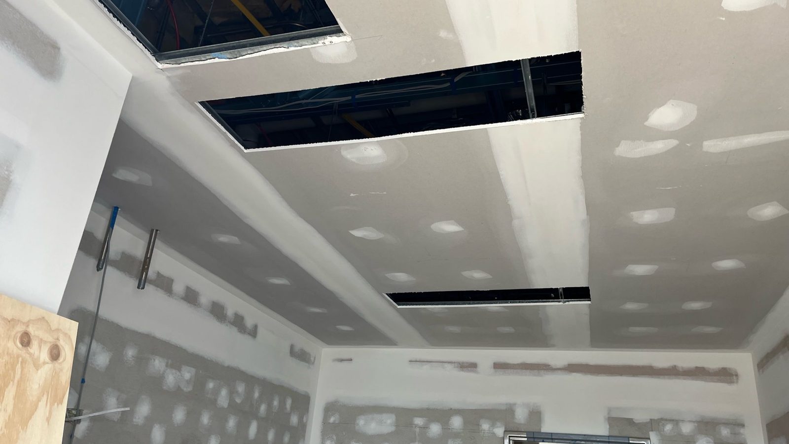 Ceiling sheeted and coated with the openings for services cut in and the wall fixings spotted