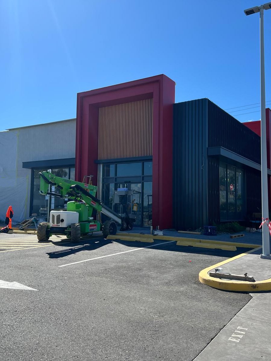 Exterior of a large commercial building with an elevated work platform parked at the front
