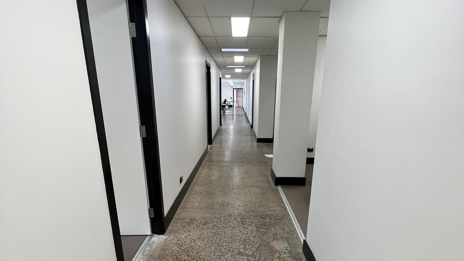 Corridor with a suspended grid ceiling finished and the walls set past a run of doors