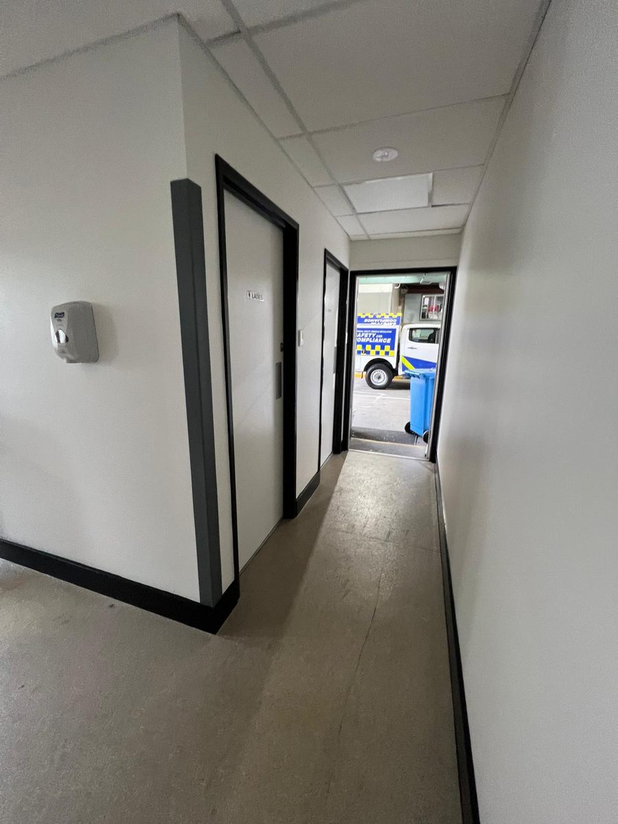 Corridor with a suspended grid ceiling and set walls running past a line of doors