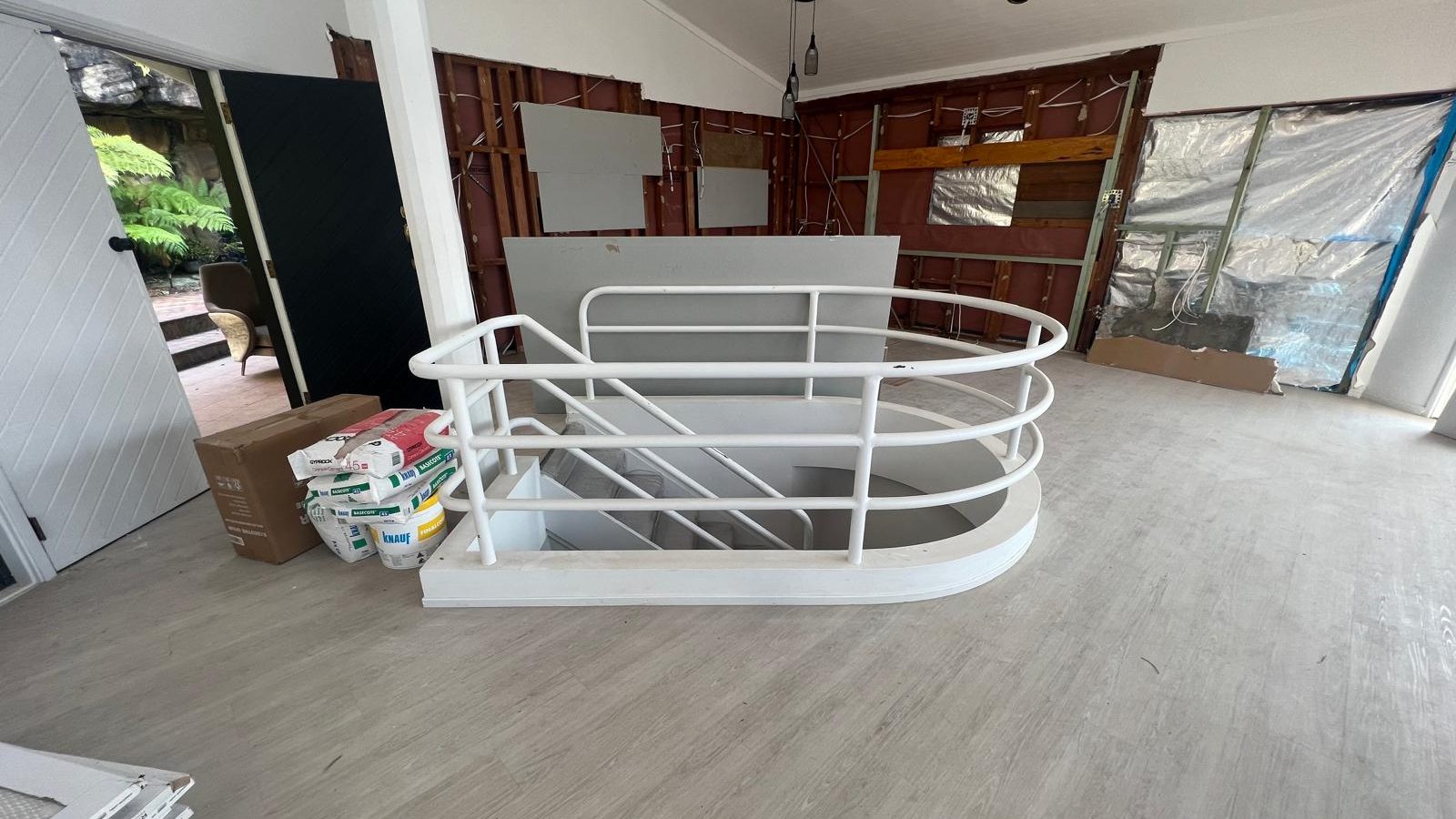 Curved balustrade around a stair void formed and set in plasterboard, with the wall framing still exposed behind