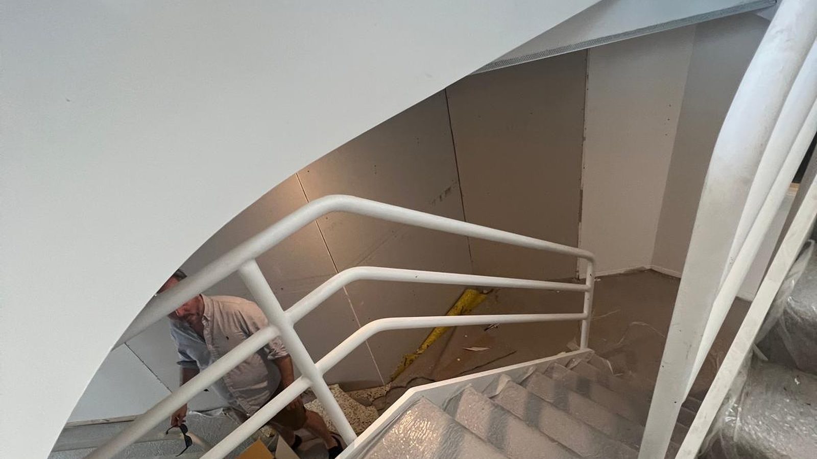 Curved plasterboard wall set above a stair, with someone finishing the floor below