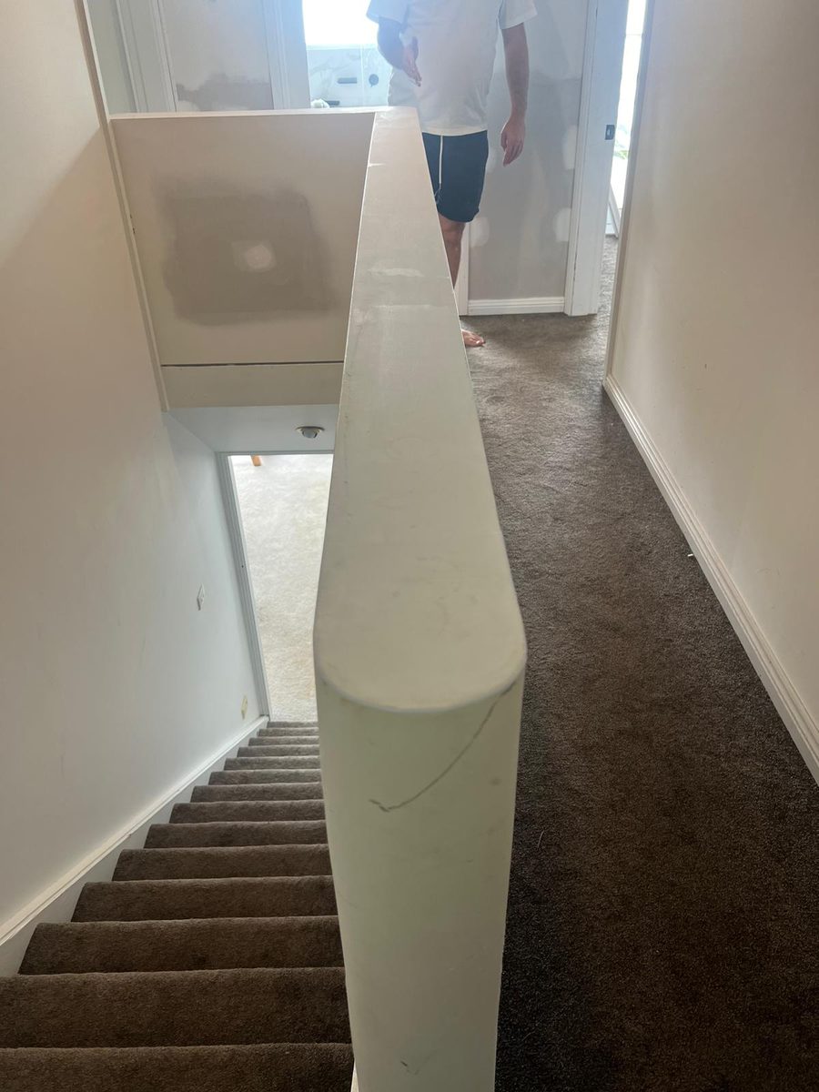 Curved plasterboard wall end formed beside a stair and set smooth