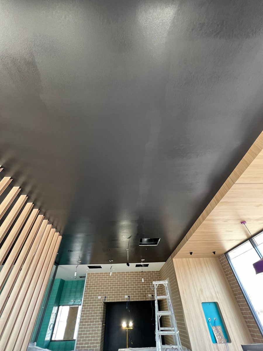 Ceiling set and finished dark over a shopfront, with a slatted wall lining below