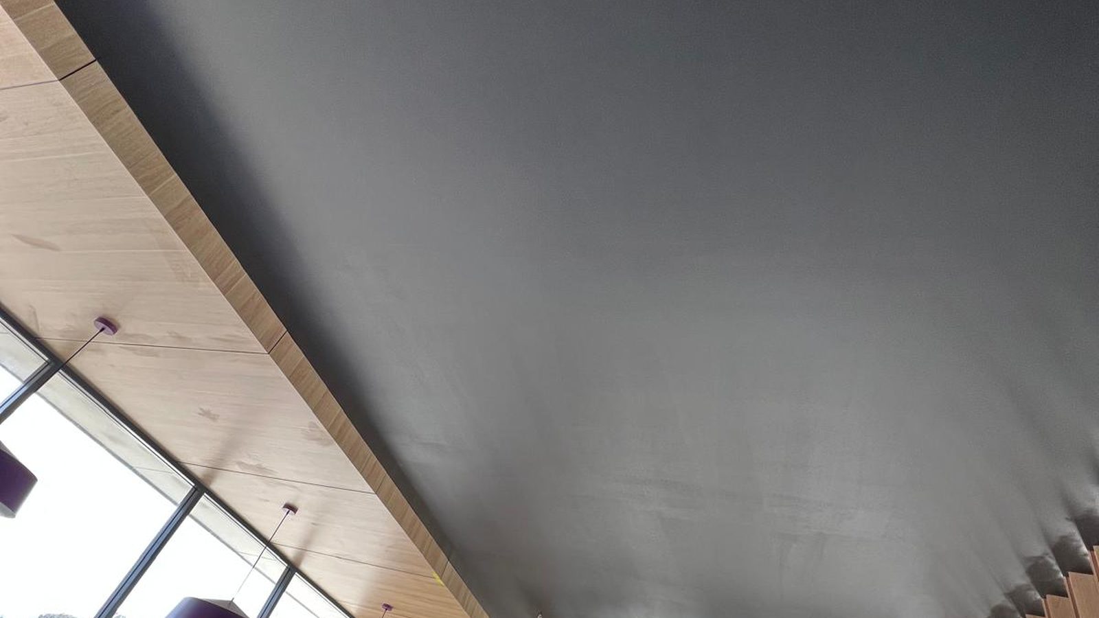 Ceiling set flush and finished dark, running to a timber lined edge above a run of glazing
