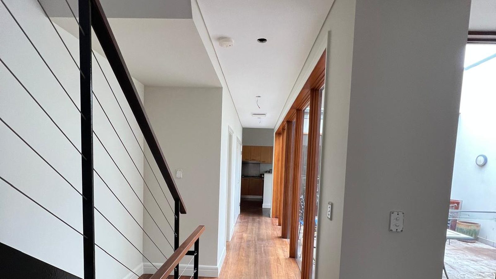 Hallway with the walls and ceiling set flush and painted, a lined stair wall to one side and doorways opening off it