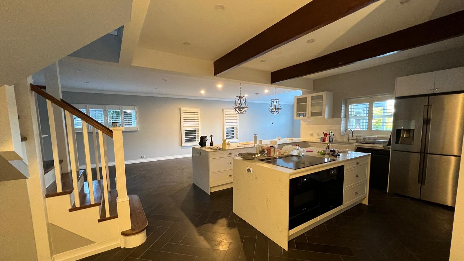 Kitchen and dining space with the ceiling set between exposed timber beams and a stair to one side