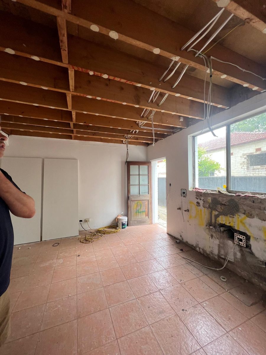 Kitchen stripped back with the ceiling opened to the rafters and the wiring left hanging