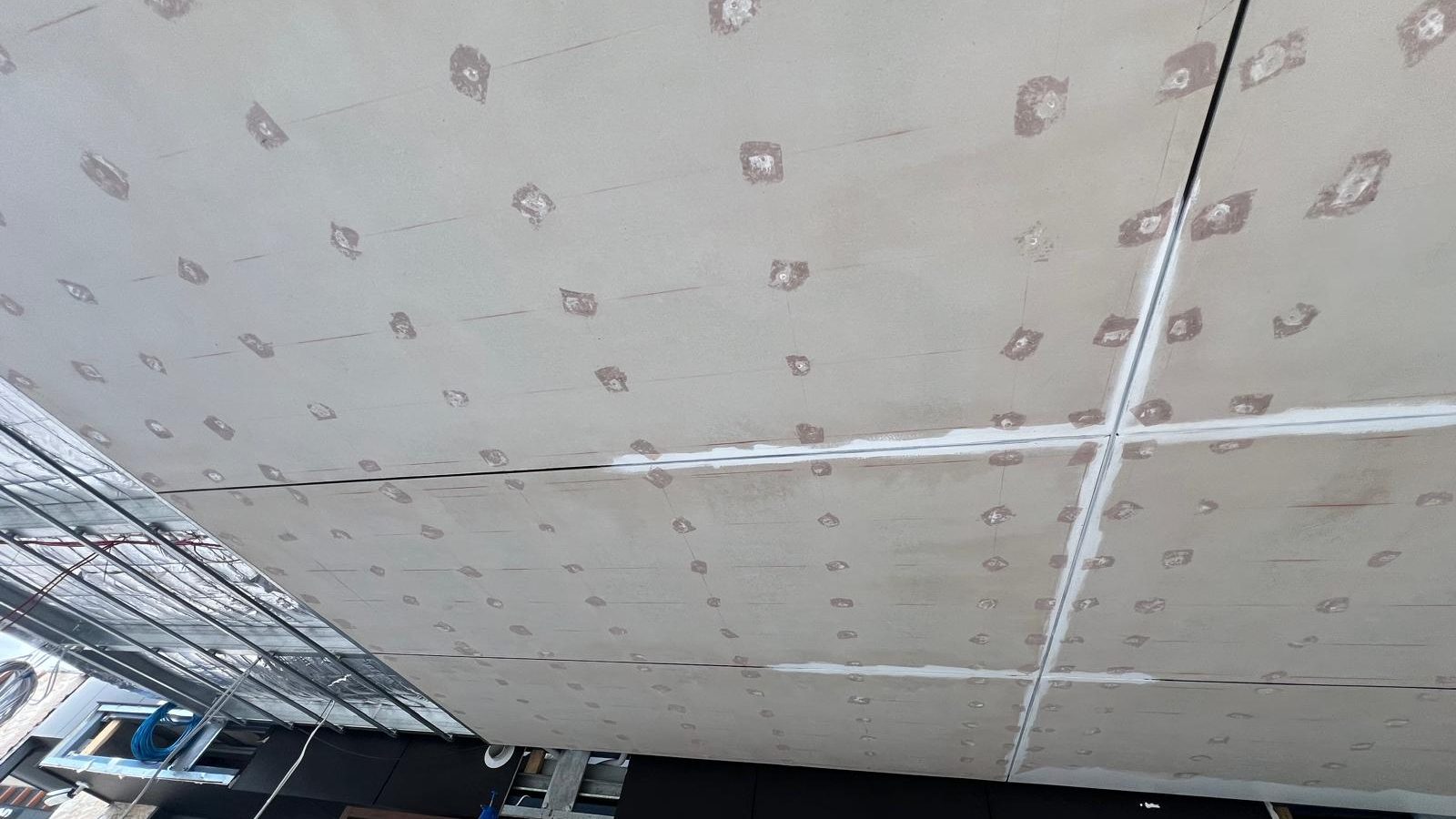 Large ceiling fully sheeted in plasterboard with every screw fixing spotted and the sheet joints taped ready for the next coat