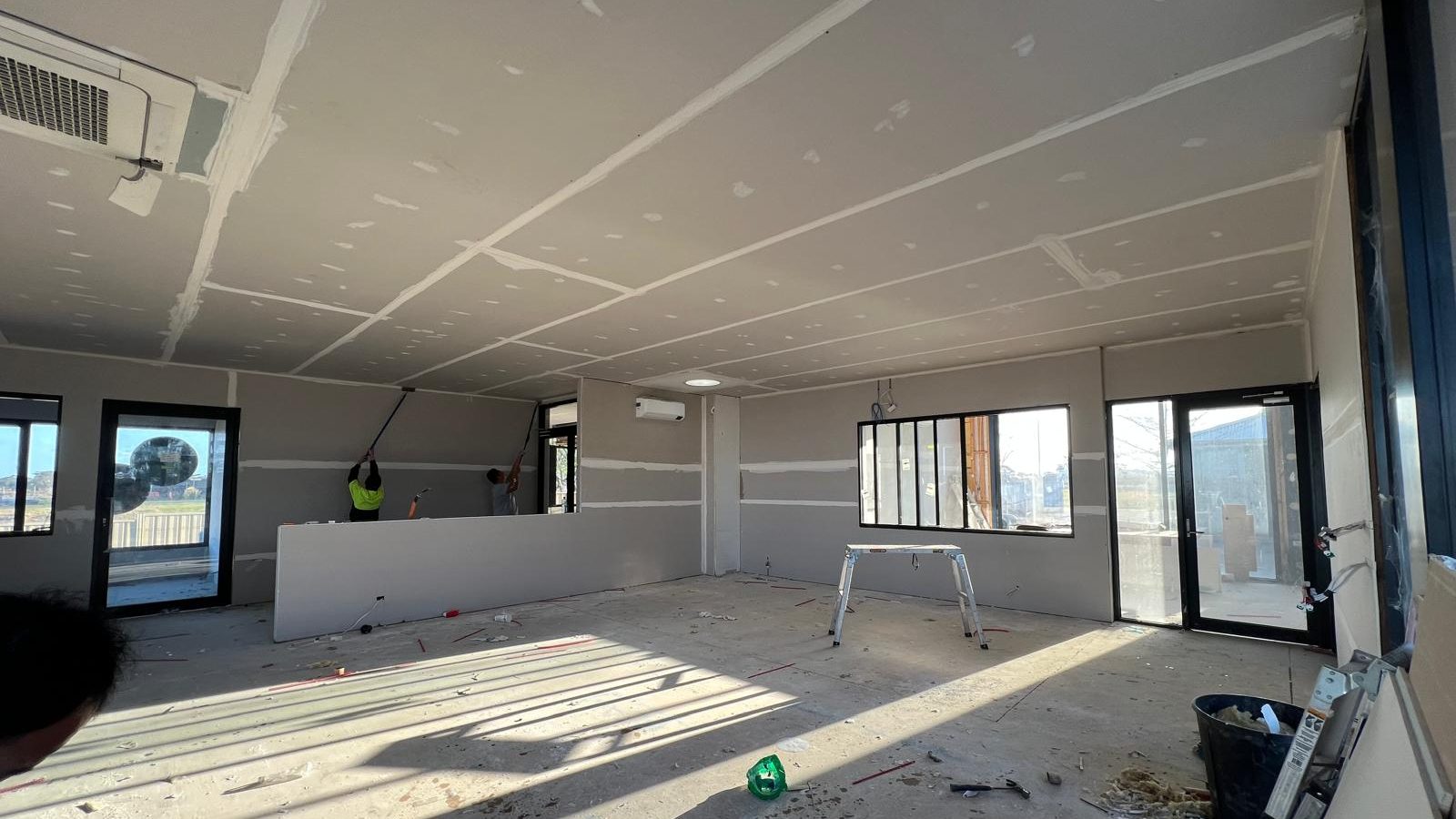 Large room sheeted and set throughout, with someone finishing the last of the wall joints