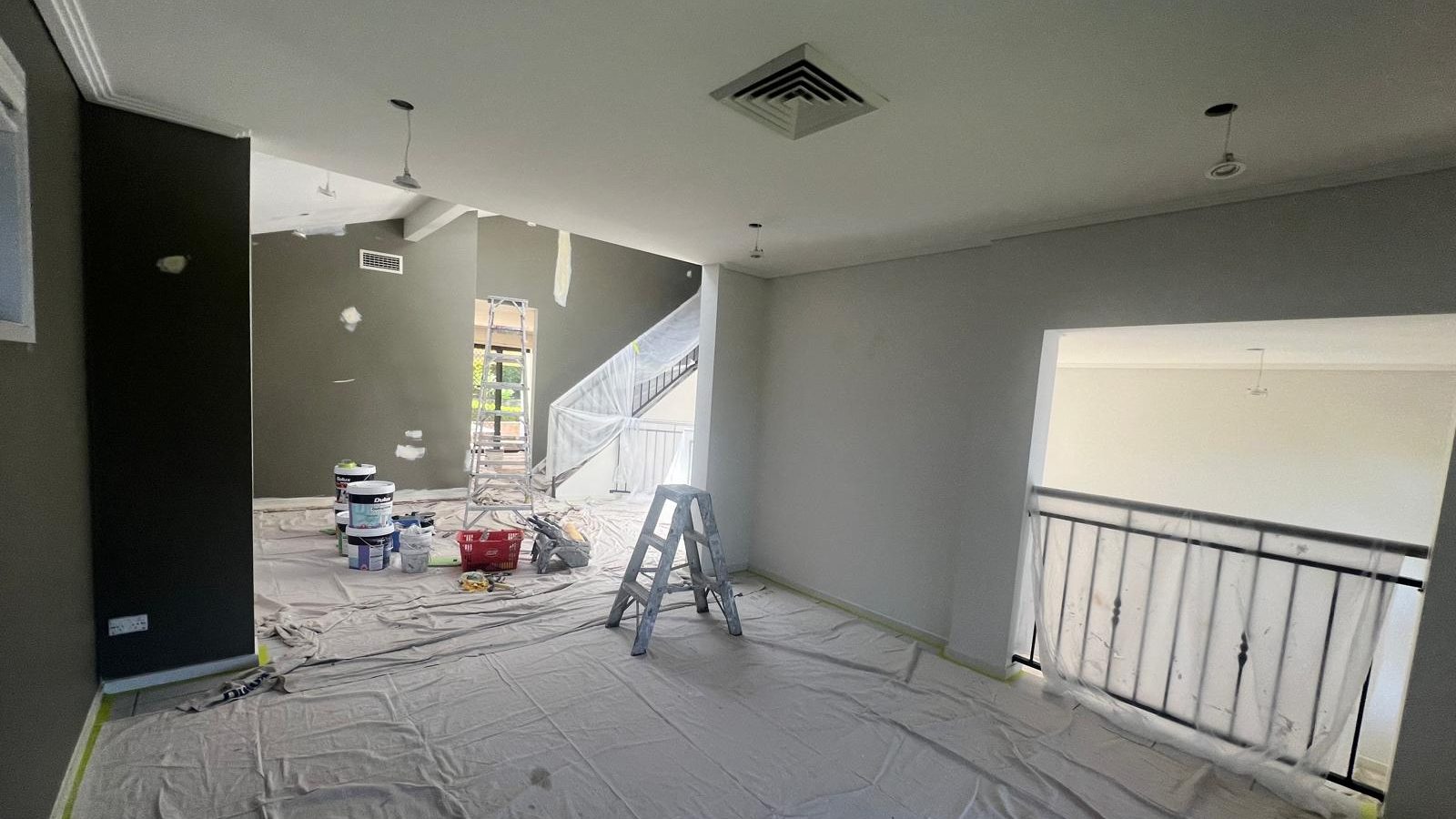 Living room with the walls and raked ceiling set and one wall finished dark, drop sheets still down
