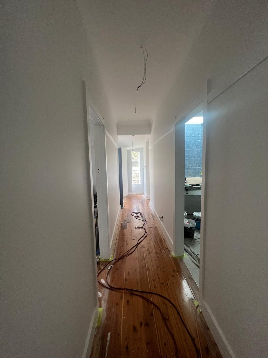 Narrow hallway with the walls and ceiling set flush and the original floorboards below
