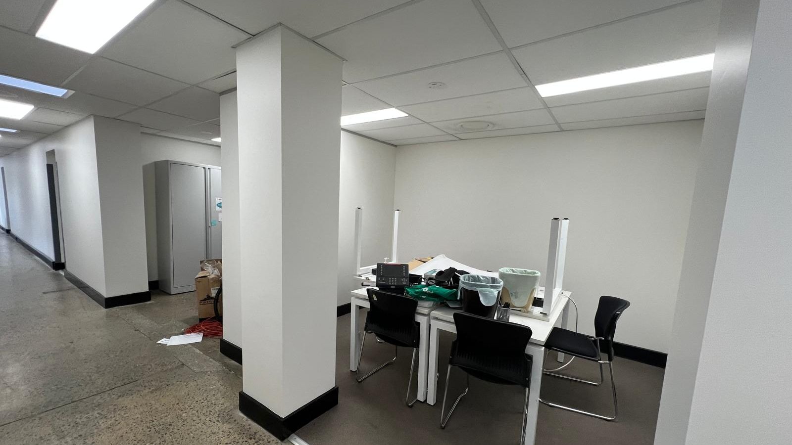 Office area with a suspended grid and tile ceiling and recessed light panels, the walls set and painted