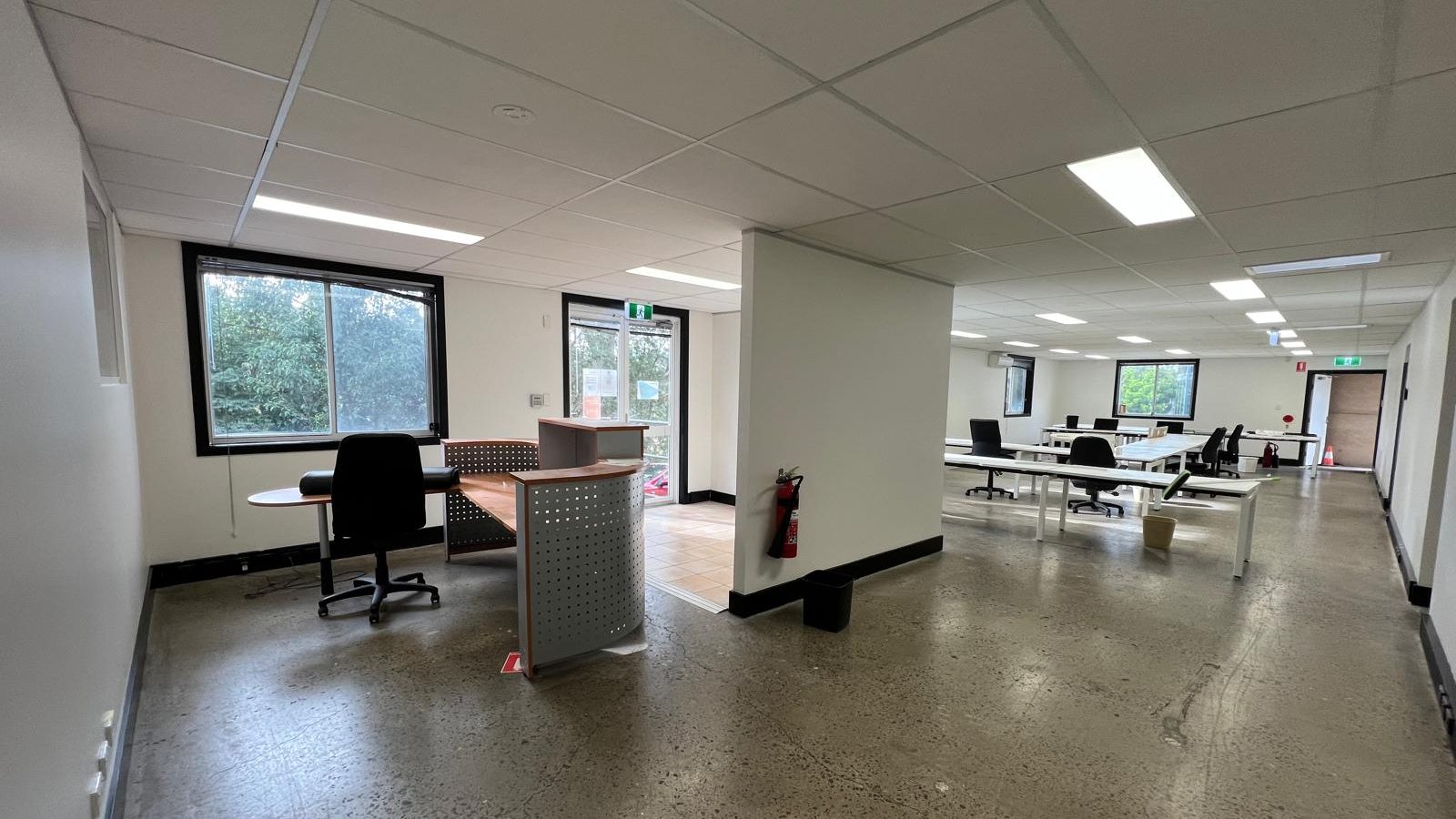 Office reception area with a suspended grid ceiling, set walls and workstations beyond