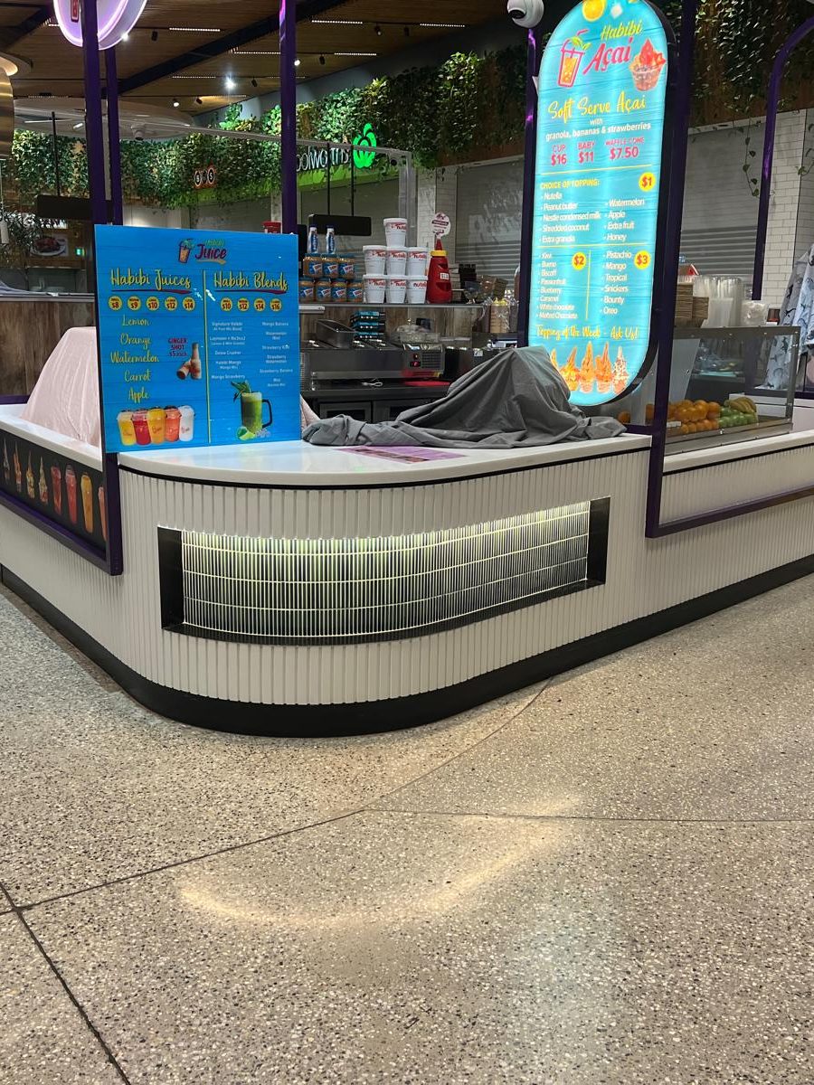 Retail counter with lit overhead panels above it and the surrounding surfaces finished