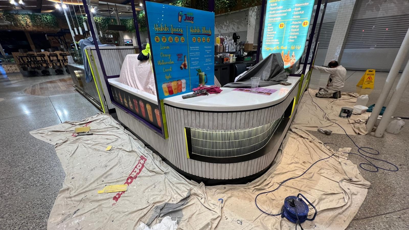 Curved retail counter with the surrounding floor protected by drop sheets while the fit out is finished