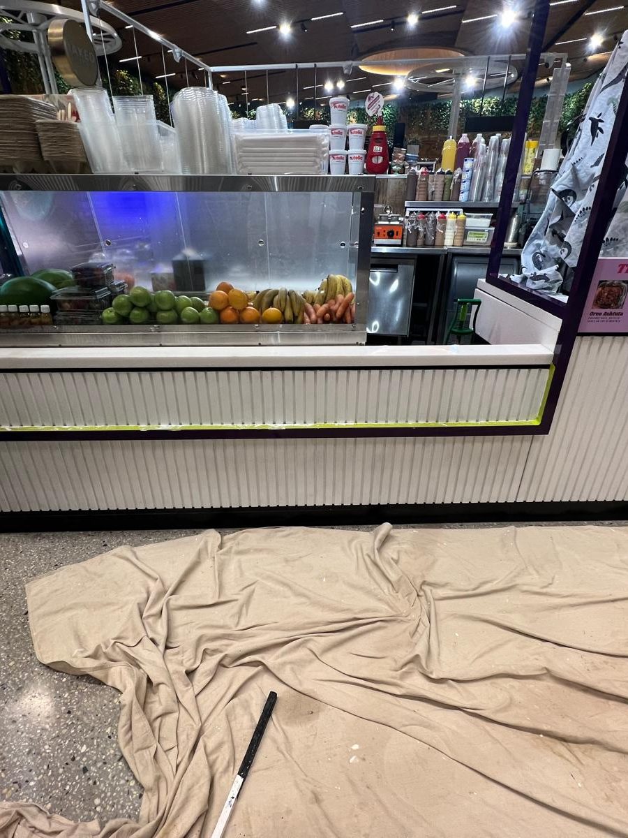 Retail counter and the overhead detail above it in a fit out, with a drop sheet laid across the floor in front