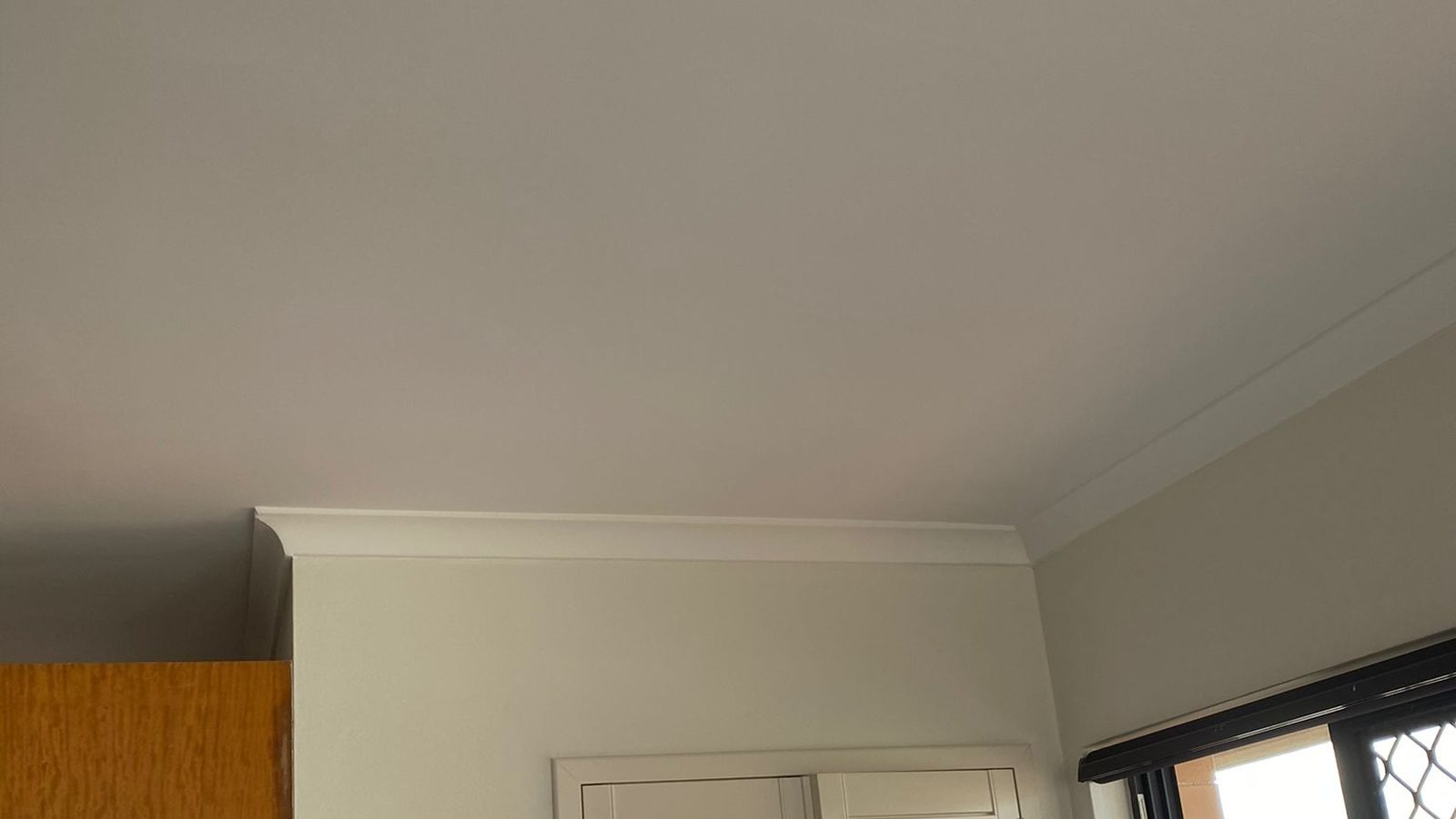 Room with the ceiling set into a run of cornice and the walls finished around the window