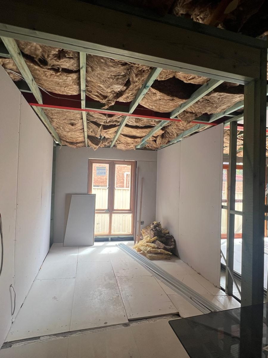 Room with the walls sheeted and the ceiling still open to the rafters and insulation above