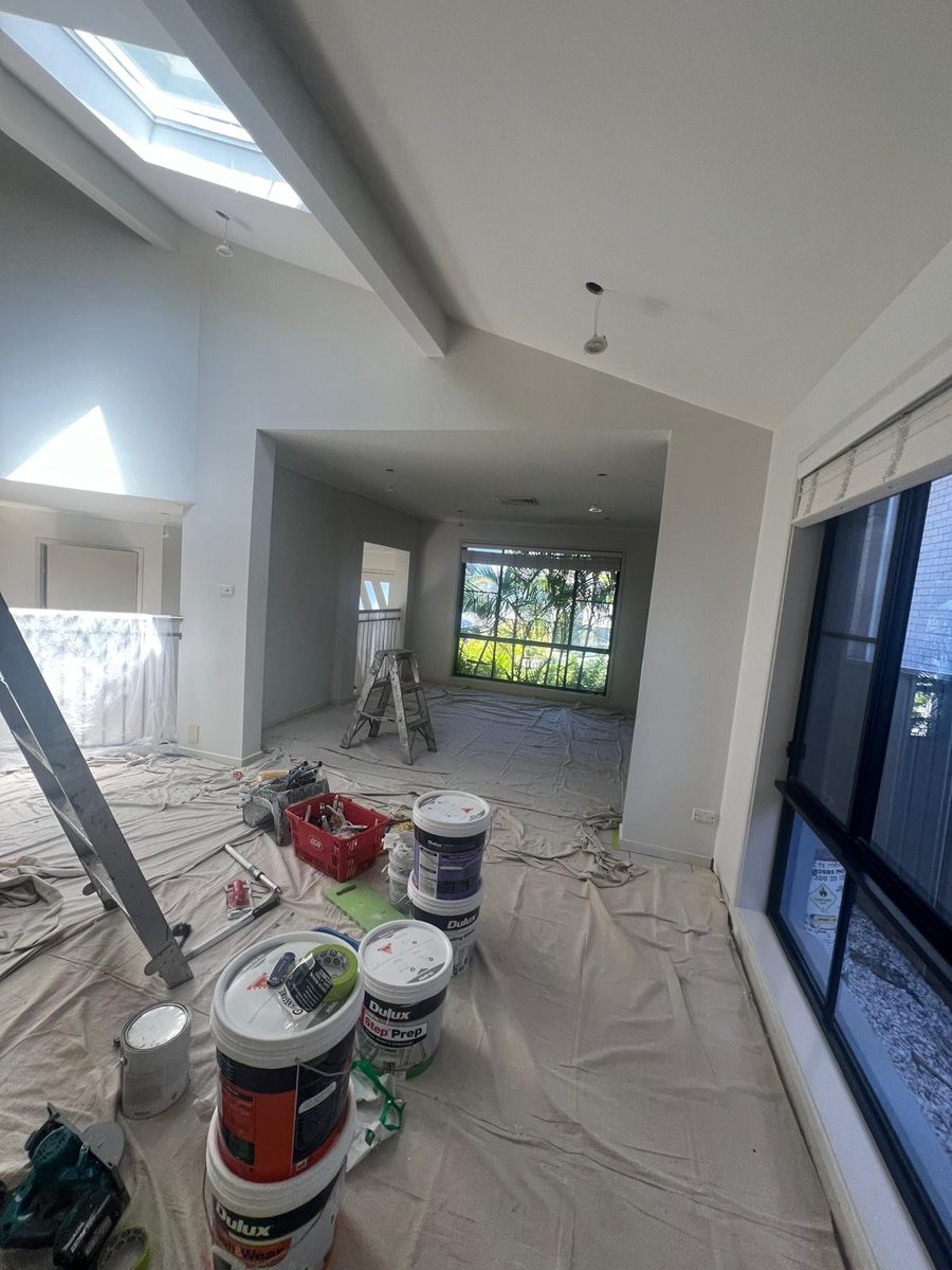 Room with a bulkhead running across the ceiling and a skylight above, drop sheets down while the walls are finished