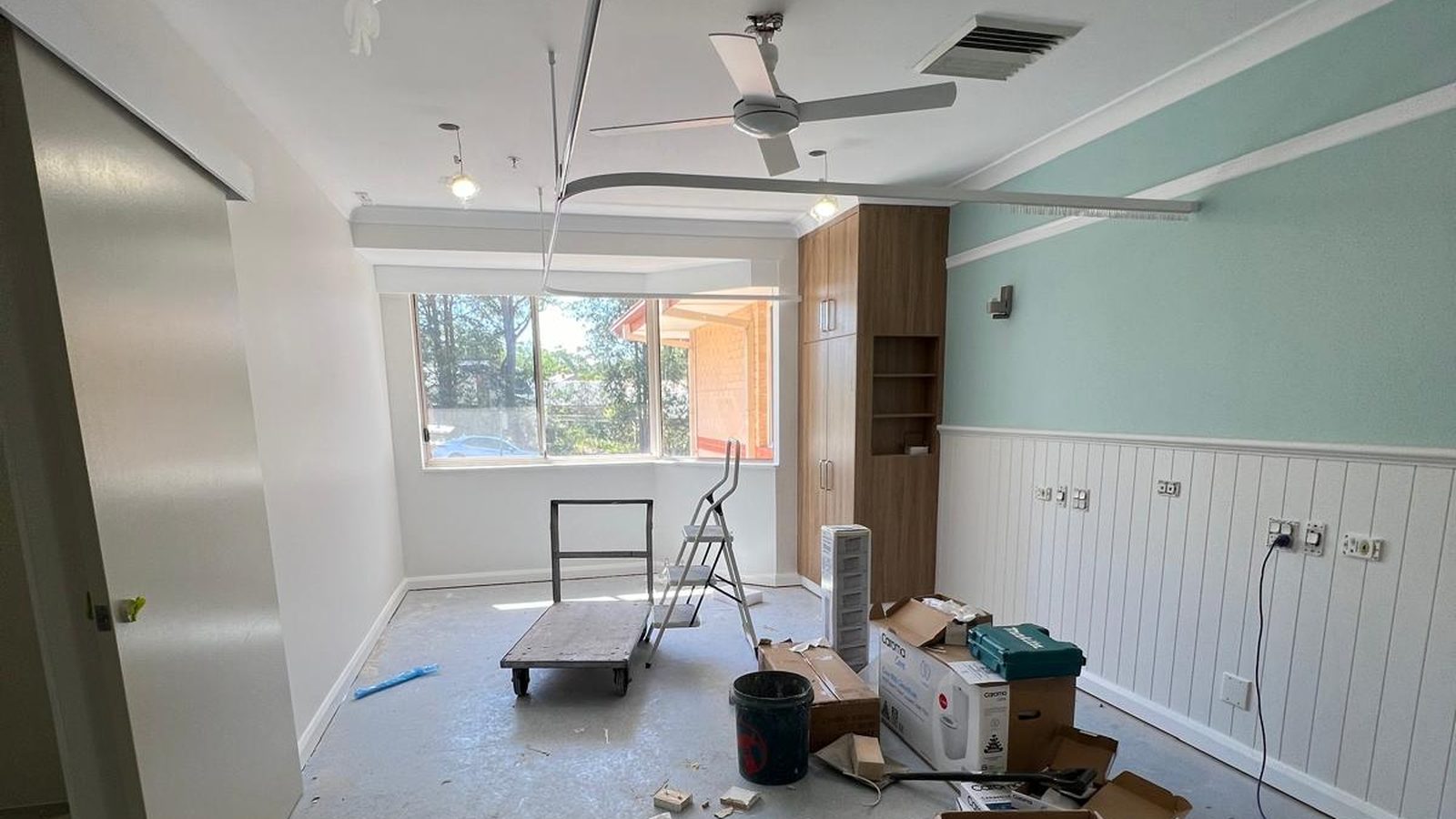 Room with a lined dado below and set walls above, the ceiling finished and equipment still on the floor