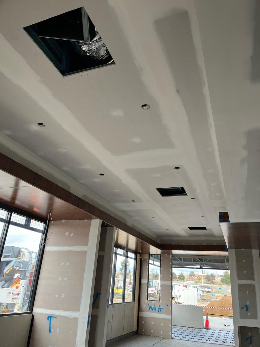 Shopfront ceiling set flush with downlights and an air outlet cut in, the glazing looking out to the street