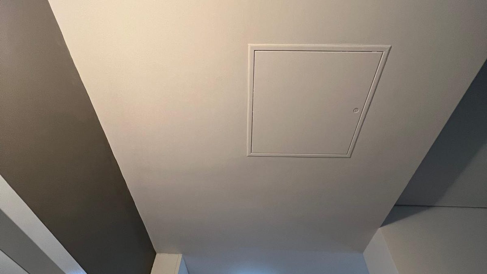 Square access panel set flush into a finished ceiling beside a bulkhead