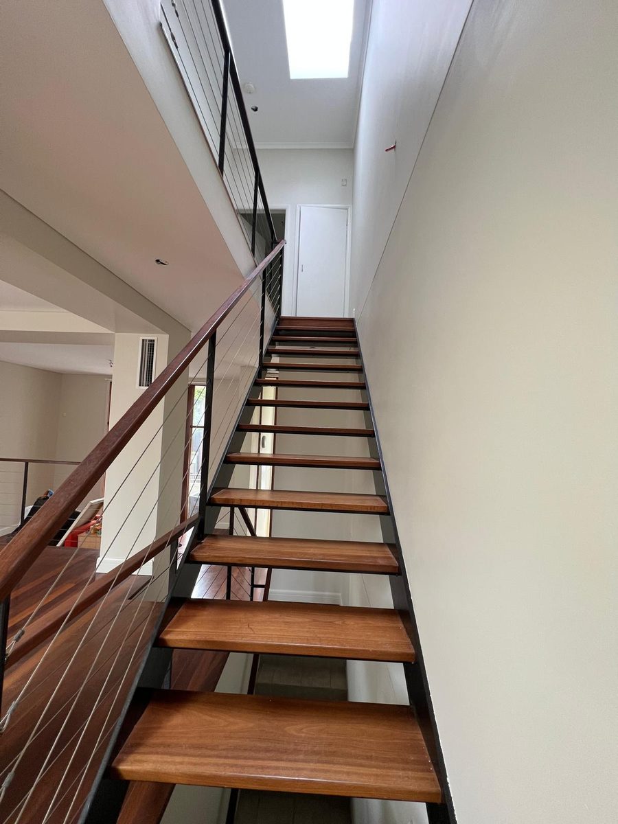 Stairwell with tall walls set flush and a skylight above the timber stair