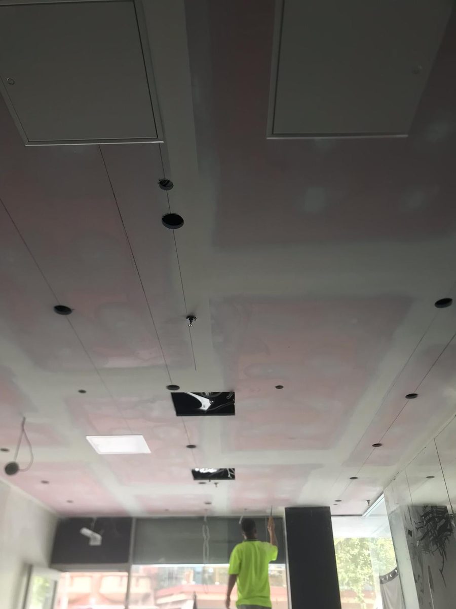 Suspended ceiling being installed, with the hangers and grid in place and the panels going in