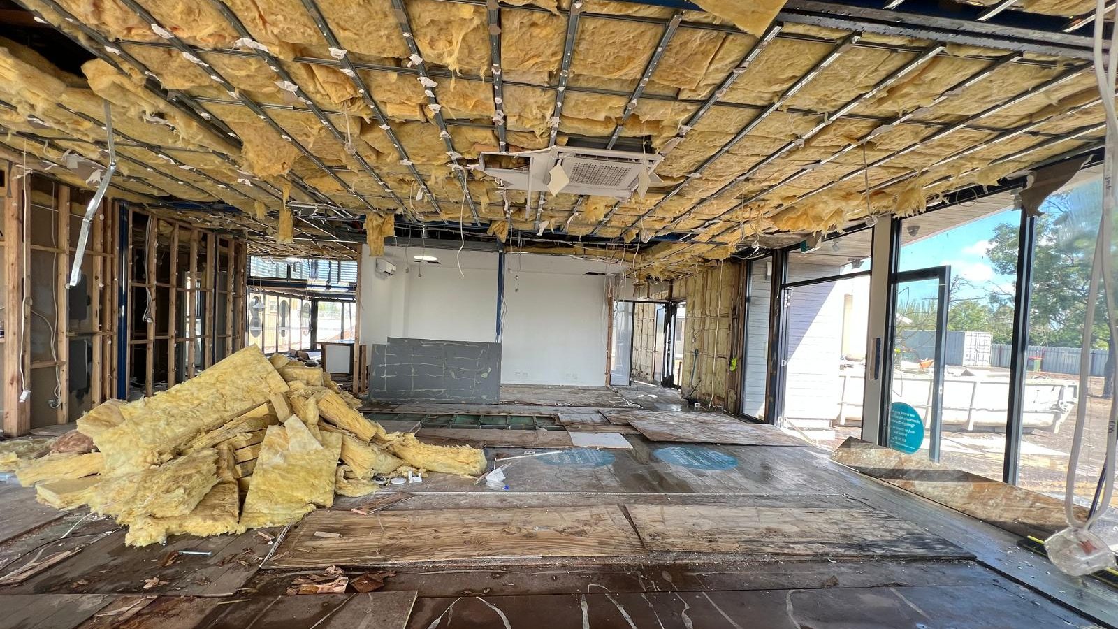 Tenancy with the ceiling stripped back to the framing and the old insulation pulled down onto the floor