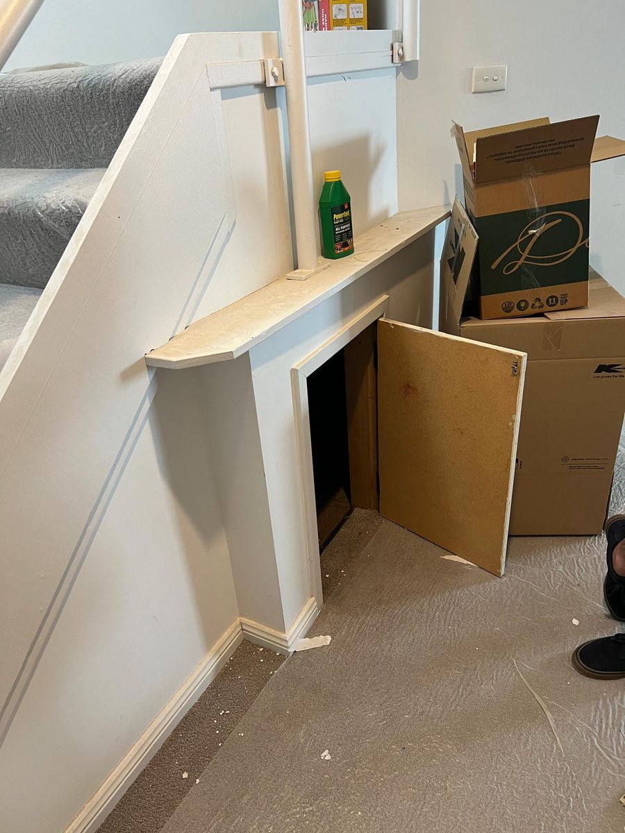 Understair storage opening lined and set into the stair wall, with the surrounding walls finished