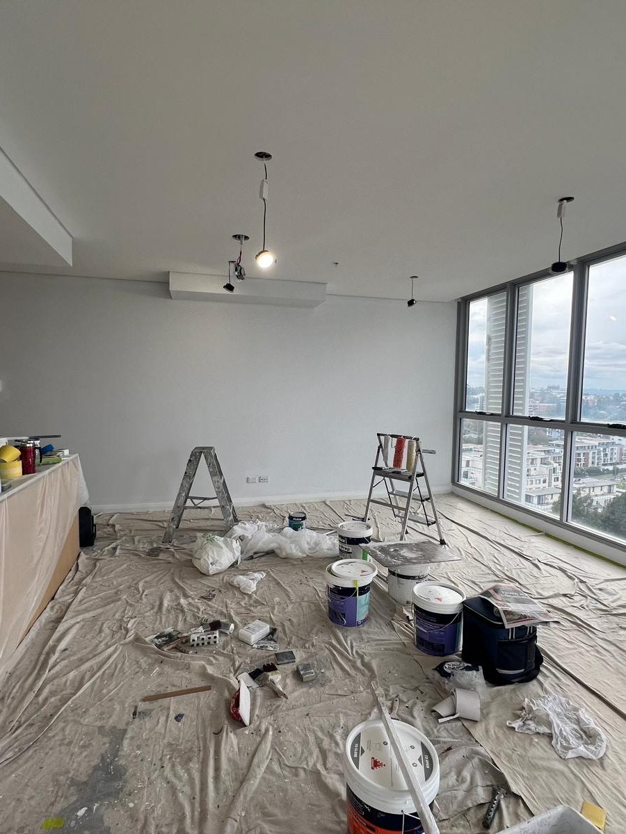 Upper floor room with the ceiling set and the walls finished, drop sheets across the floor