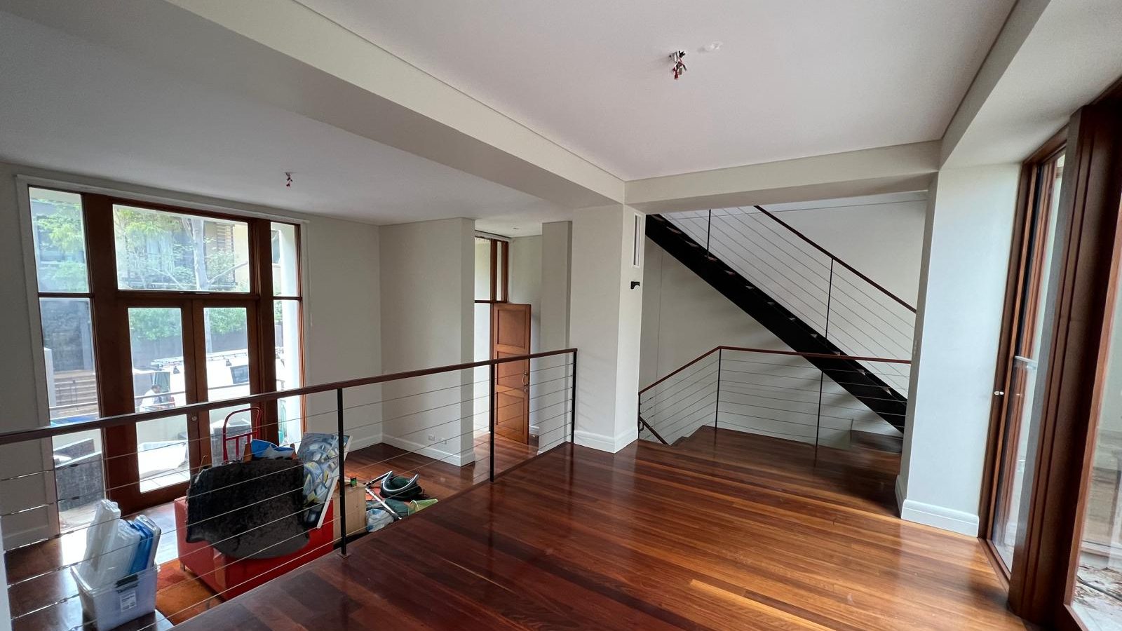 Upper landing with the walls and ceiling set and painted, a wire balustrade to the stair and a polished timber floor