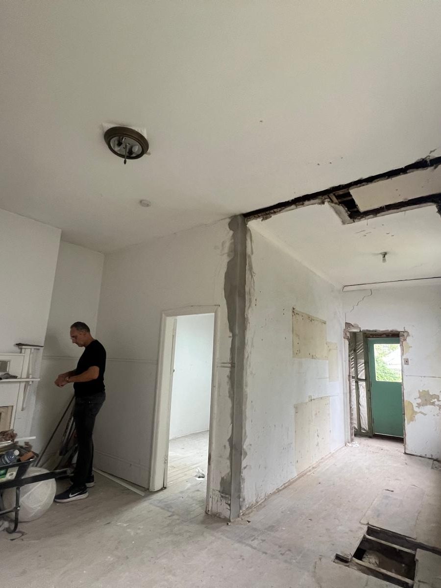 Room with the ceiling set and one wall opened back to the masonry, with someone clearing up below