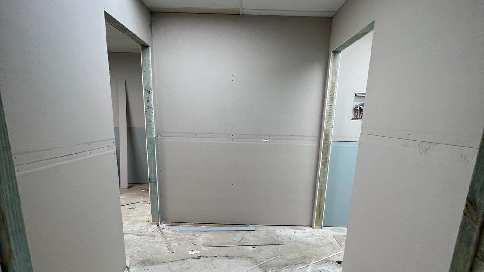 Wall newly sheeted in plasterboard around two door openings, the sheets fixed and the joints not yet set
