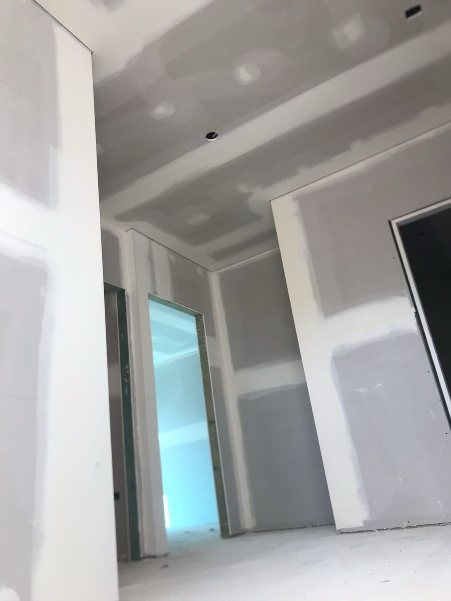 Walls sheeted and set around a glazed opening, the surfaces coated and ready to sand